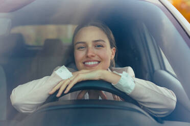 Aufgeregte junge Frau, die in ihrem Auto sitzt und sich auf eine Fahrt vorbereitet. - HPIF11734