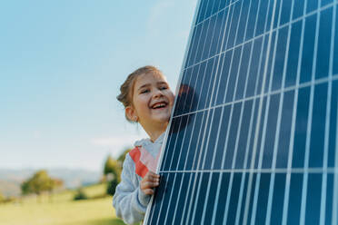 Kleines Mädchen, das ein Photovoltaik-Solarpanel in der Hand hält: Alternative Energie, Ressourcenschonung und nachhaltiger Lebensstil. - HPIF11751