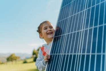 Little girl holding a photovoltaics solar panel. Alternative energy, saving resources and sustainable lifestyle concept. - HPIF11751