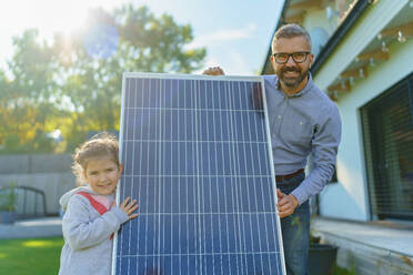 Father with his little daughter near the house with solar panels. Alternative energy, saving resources and sustainable lifestyle concept. - HPIF11753