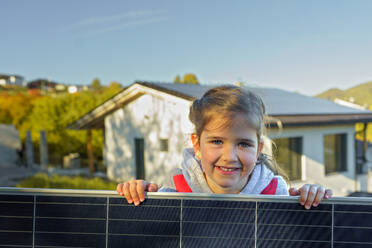 Kleines Mädchen, das ein Photovoltaik-Solarpanel in der Hand hält: Alternative Energie, Ressourcenschonung und nachhaltiger Lebensstil. - HPIF11776