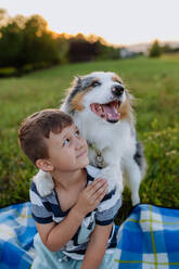 Kleiner Junge mit Hund im Freien, beim Picknick. - HPIF11824