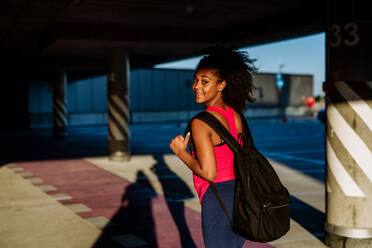 Multiracial Teenager-Mädchen zu Fuß mit einem Rucksack in der modernen Stadt während des Sommers Tag, zurück zu Schule Konzept. - HPIF11936