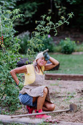 Ältere Frau, die sich nach der Gartenarbeit ausruht und Schmerzen im Rücken hat. - HPIF11960