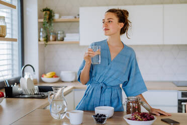 Young woman preparing a muesli for breakfast in her kitchen, morning routine and healthy lifestyle concept. - HPIF12009