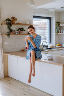 Junge Frau genießt eine Tasse Kaffee am Morgen in einer Küche. - HPIF12018