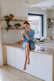 Young woman enjoying cup of coffee at morning, in a kitchen. - HPIF12018