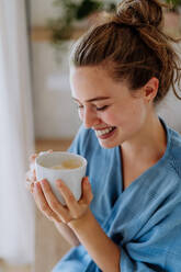 Junge Frau genießt eine Tasse Kaffee am Morgen in einer Küche. - HPIF12019