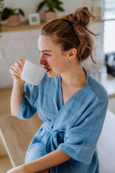 Junge Frau genießt eine Tasse Kaffee am Morgen in einer Küche. - HPIF12020