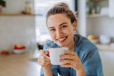 Junge Frau genießt eine Tasse Kaffee am Morgen in einer Küche. - HPIF12025