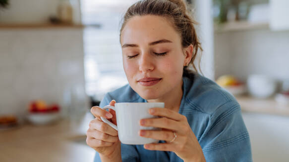 Junge Frau genießt eine Tasse Kaffee am Morgen in einer Küche. - HPIF12026
