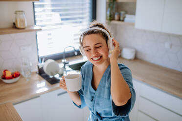 Young woman enjoying cup of coffee and listening music at morning, in a kitchen. - HPIF12038