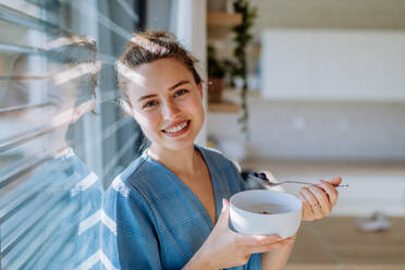 Junge Frau mit einem Müsli zum Frühstück in ihrer Küche, Morgenroutine und gesunder Lebensstil Konzept. - HPIF12041