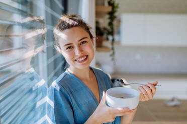 Young woman having a muesli for breakfast in her kitchen, morning routine and healthy lifestyle concept. - HPIF12041