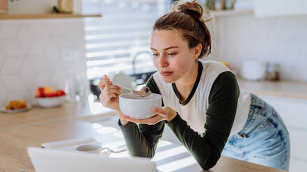 Junge Frau mit einem Müsli zum Frühstück in ihrer Küche, Morgenroutine und gesunder Lebensstil Konzept. - HPIF12053