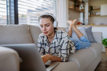 Junge Frau ruht sich auf dem Sofa aus und lauscht der Musik. - HPIF12102