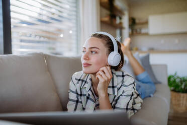 Young woman resting on sofa and listening the music. - HPIF12104