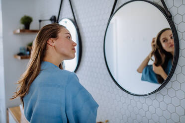 Junge Frau, die sich um ihr Haar kümmert, Konzept der morgendlichen Schönheitsroutine. - HPIF12124