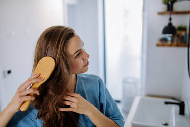 Young woman taking care of hair, morning beauty routine concept. - HPIF12125