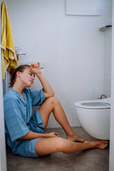 Young pregnant woman sitting on floor near toilet. - HPIF12141