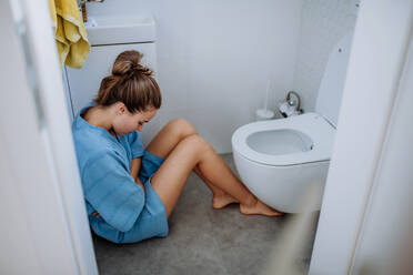 Young pregnant woman sitting on floor near toilet. - HPIF12143