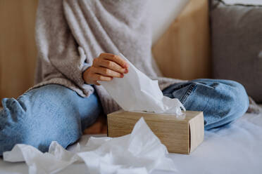 Kranke Frau im Bett sitzend, erkältet, Nahaufnahme der Papiertaschentücher. - HPIF12147