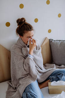 Kranke Frau, die mit einer Erkältung in einem Bett sitzt. - HPIF12148