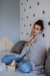 Kranke Frau, die mit einer Erkältung in einem Bett sitzt. - HPIF12149