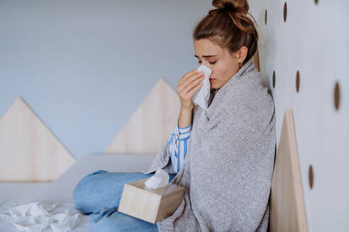 Kranke Frau, die mit einer Erkältung in einem Bett sitzt. - HPIF12150