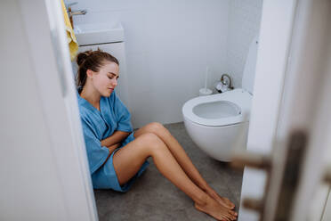 Young pregnant woman sitting on floor near toilet. - HPIF12165