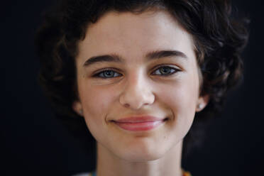 Porträt eines selbstbewussten schönen Teenagers, der in die Kamera schaut, auf schwarzem Hintergrund, Nahaufnahme - HPIF12178