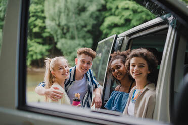 Multiracial young friends travelling together by car, looking through the window and smiling - summer vacation, holidays, travel, road trip and people concept. - HPIF12195