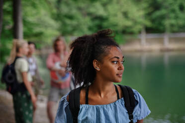 Porträt eines jungen gemischtrassigen Mädchens mit Freunden auf einem Campingausflug am See im Sommer. - HPIF12209