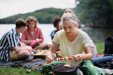 Eine Gruppe multirassischer junger Freunde zeltet am See und grillt gemeinsam. - HPIF12222