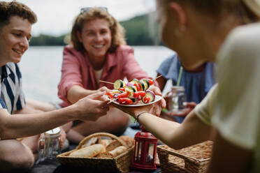 Eine Gruppe junger Freunde, die in der Nähe eines Sees zelten und gemeinsam grillen, Nahaufnahme. - HPIF12224