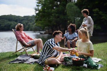 Eine Gruppe multirassischer junger Freunde zeltet am See und grillt gemeinsam. - HPIF12229