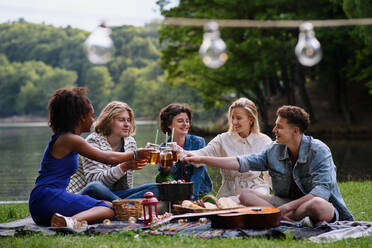 A group of multiracial young friends camping near lake and and having barbecue together. - HPIF12260