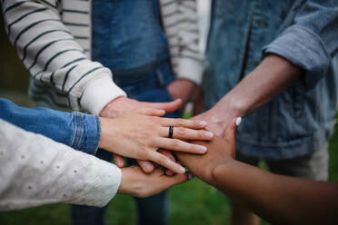 A close-up of diverse group of friends stacking their hands together in circle, Friendship and lifestyle concepts - HPIF12279