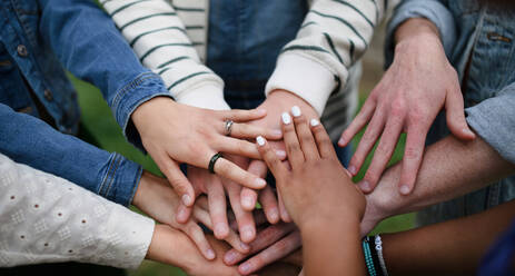 A close-up of diverse group of friends stacking their hands together in circle, Friendship and lifestyle concepts - HPIF12280