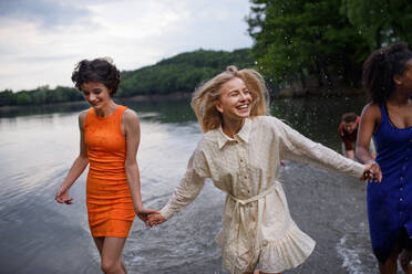 A multiracial group of young friends holding hands,standing in lake in summer and having fun. - HPIF12288