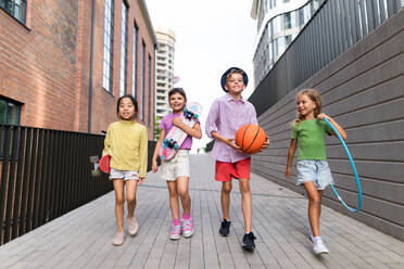 Fröhliche Kinder spielen und unterhalten sich in der Stadt, während des Sommertages, mit Blick auf die Kamera. - HPIF12348