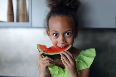 Multirassische Mädchen, die an heißen Sonnentagen in der Küche eine Melone essen. - HPIF12391