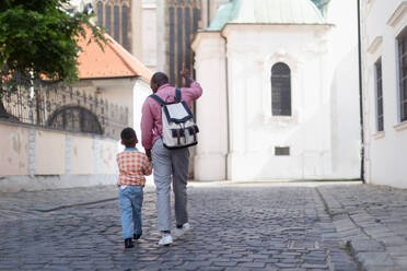 Ein gemischtrassiger Vater mit seinem kleinen Sohn, der gemeinsam durch die Altstadt spaziert. - HPIF12405