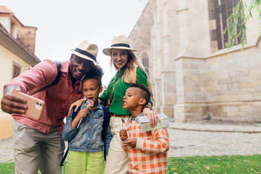 Eine vielseitige Familie, die das historische Stadtzentrum erkundet und Erinnerungen mit einem Selfie und ihren Kindern festhält - HPIF12407