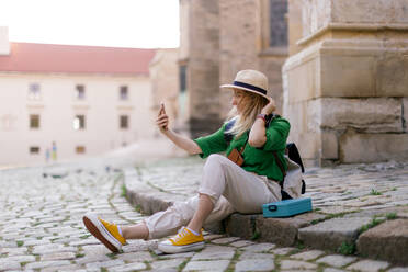 Eine junge Frau erkundet das historische Stadtzentrum, hält Erinnerungen mit ihrem Handy fest und macht ein Selfie - HPIF12416