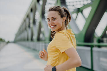 Junge Frau joggt auf einer Stadtbrücke, gesunder Lebensstil und Sportkonzept. - HPIF12440
