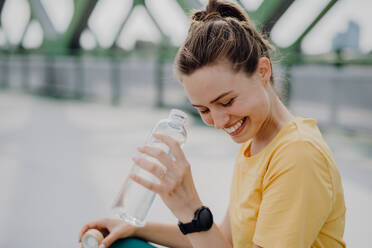 Junge Frau trinkt Wasser beim Joggen in einer Stadt, gesunder Lebensstil und Sportkonzept. - HPIF12444