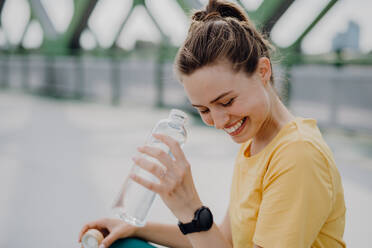 Young woman drinking water during jogging in a city, healthy lifestyle and sport concept. - HPIF12444