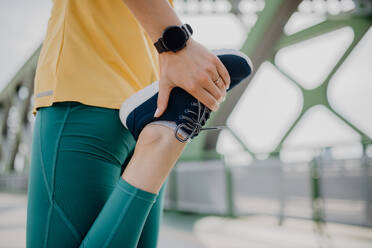 Close-up of woman doing stretching in a city, preparing for run, healthy lifestyle and sport concept. - HPIF12461