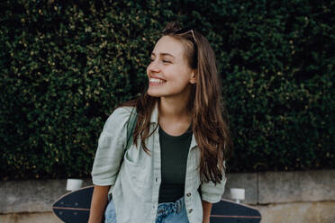 Porträt der jungen glücklichen Frau im Freien mit einem Skateboard. Jugendkultur und Pendeln Konzept. - HPIF12481